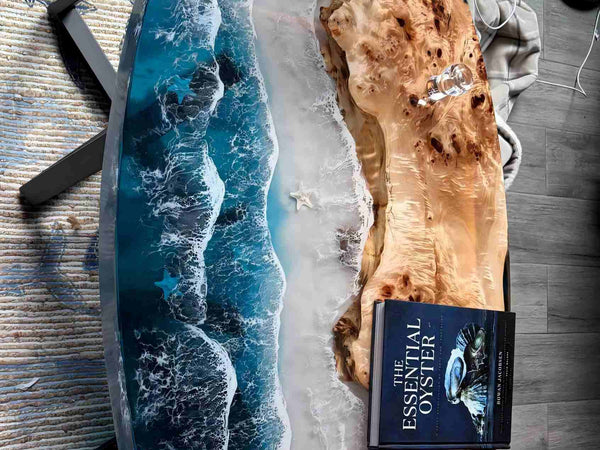 Book titled 'The Essential Oyster' on a wooden surface with a blue resin art piece.
