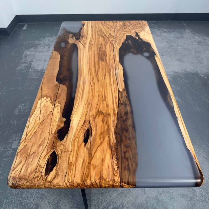 Wooden table with a dark resin finish on a gray floor.