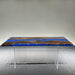 Dining table with blue resin top and wooden accents on a gray floor.