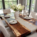 Dining room with a wooden table set for a meal, featuring white chairs and a vase of flowers.