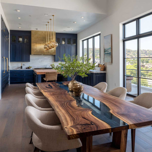 Modern dining room with a long wooden table and chairs, large windows, and blue kitchen.