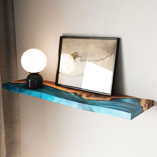 Wooden shelf with blue resin finish, lamp, and framed picture on a wall.