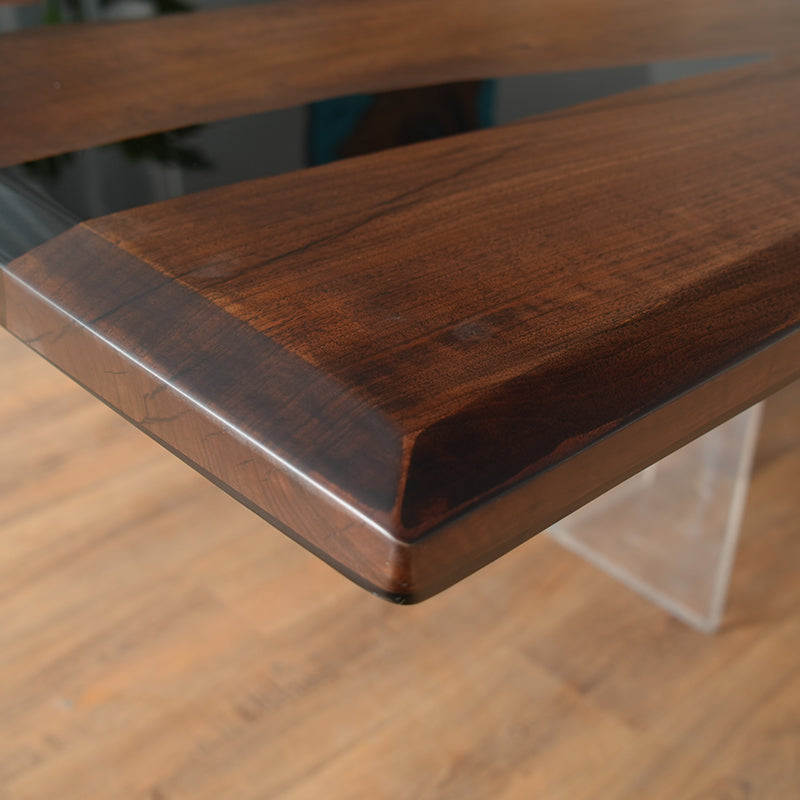 The Custom Black Walnut Epoxy River Table showcases a black walnut live edge slab, seamlessly combined with high-quality epoxy resin to create a stunning contrast. The table top epoxy finish enhances the natural wood grain while providing durability and a glossy shine. Perfect as an epoxy dining table, conference table, or a statement wood and epoxy table for modern interiors. Designed with acrylic legs, this epoxy resin wood table exudes elegance and sophistication. 