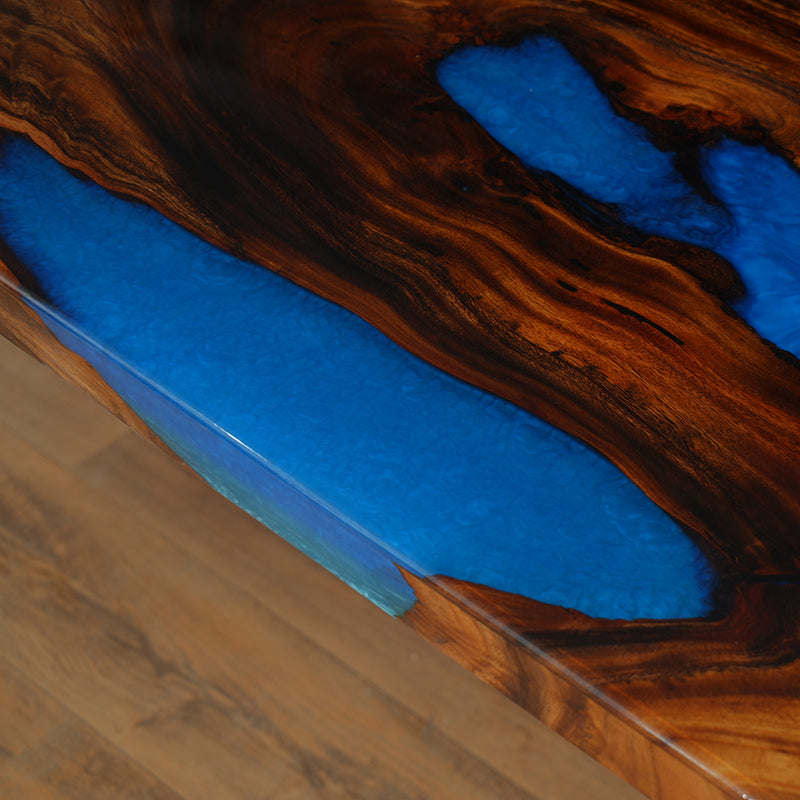 Blue epoxy resin river table featuring a high-gloss finish and natural wood slab, perfect for dining or conference rooms