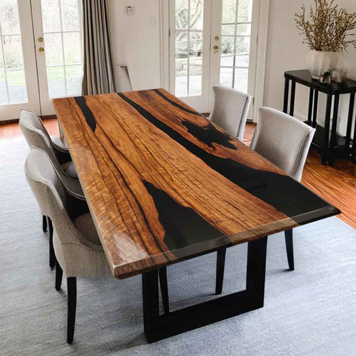 Dining table with a unique wood and black resin design in a room with chairs and decor.