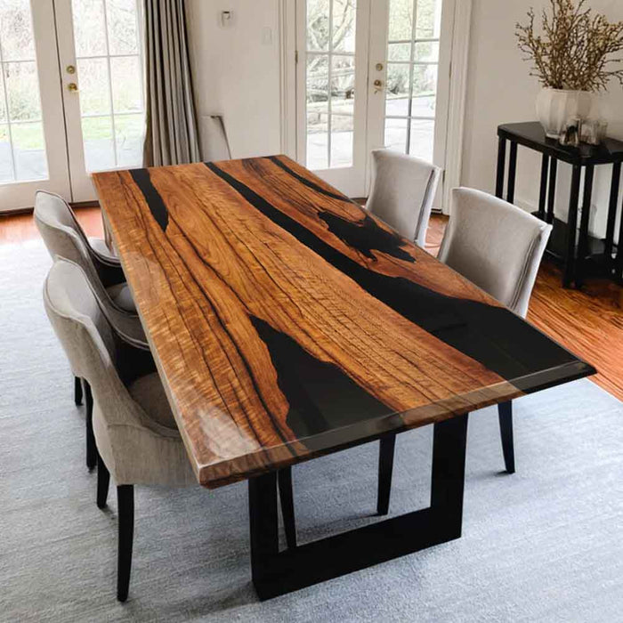 Dining table with a unique wood and black resin design in a room with chairs and decor.