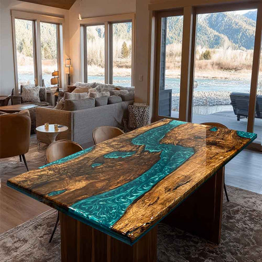 Wooden table with blue resin inlay in a modern living room with large windows overlooking a scenic view.