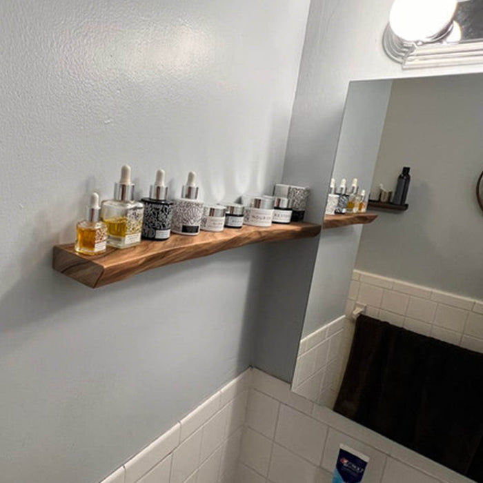 Bathroom shelf with various bottles against a gray wall.