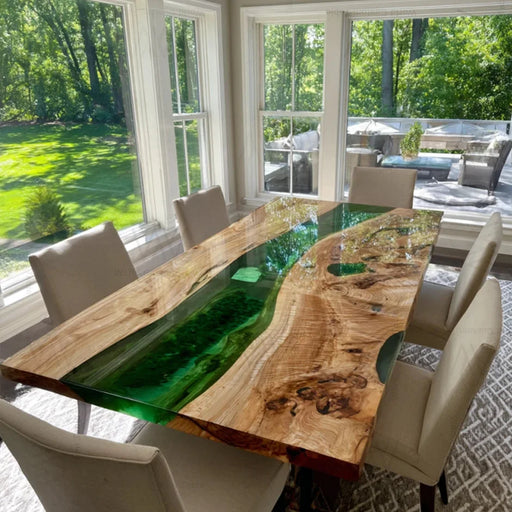 Closeup of emerald green resin flowing through white poplar wood on dining table