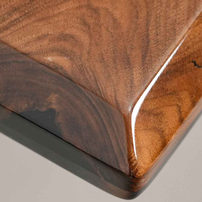 Close-up of a wooden cutting board with a dark brown finish on a gray background