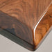 Close-up of a wooden cutting board with a dark brown finish on a gray background