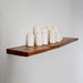 Wooden shelf with white candles on a plain wall