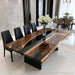 Modern black walnut river table placed in a luxury dining space, highlighting the contrast between natural wood and glossy black epoxy resin.