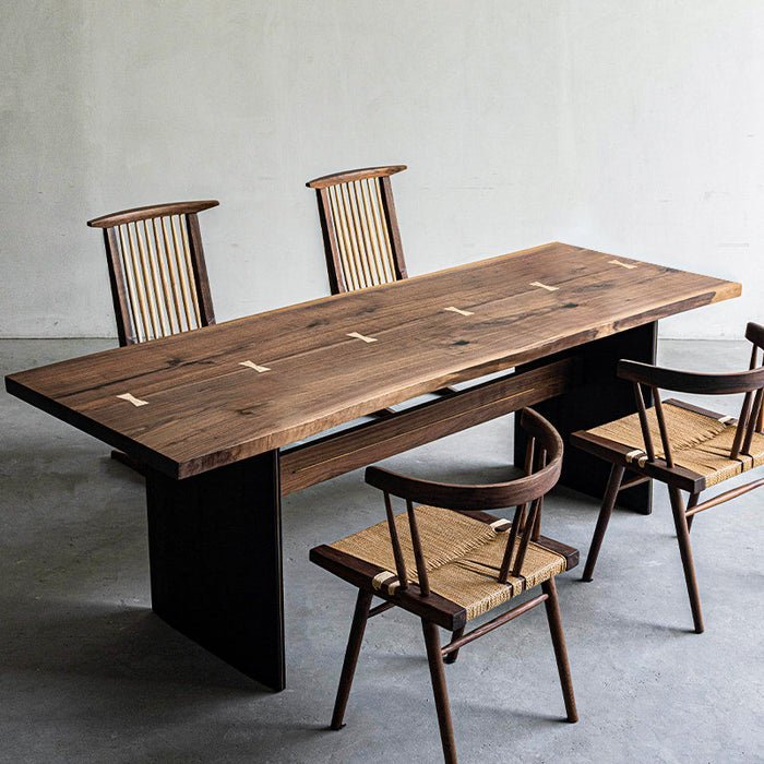 Artisan live edge walnut dining table with black metal base and woven seat chairs.