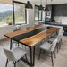 Black epoxy river dining table in a modern kitchen with mountain view.