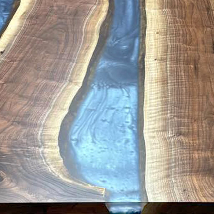 Handcrafted river table with glowing resin and raw-edge black walnut slabs.