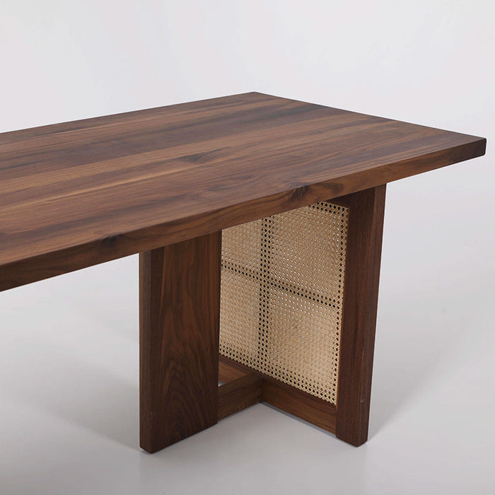 Black walnut dining table with woven rattan leg panels