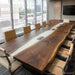A black walnut epoxy conference table placed in a luxury executive boardroom setting with modern chairs.