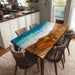 Dining table with wooden surface and blue resin finish in a kitchen setting
