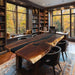 Modern home office with a large wooden desk, bookshelves, and large windows showing autumn foliage.