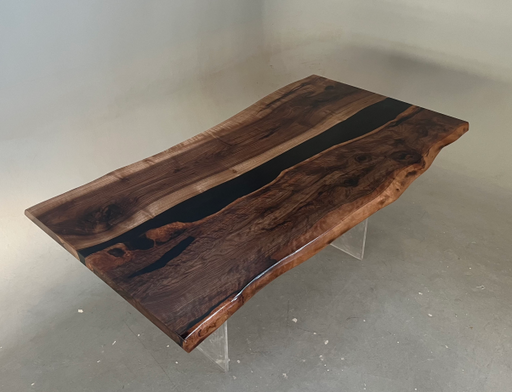 Wooden dining table with a black resin inlay on a gray floor.