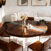 Round wooden dining table with four brown chairs in a modern living room.
