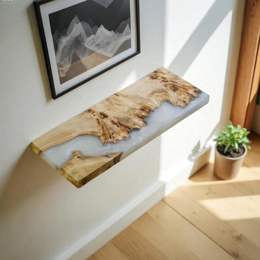 Wooden console table with epoxy finish against a white wall with a framed picture.