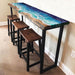 Coastal-style resin and wood high bar table set with matching stools, perfect for kitchen islands or patios.