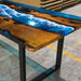 Wooden table with a blue resin design resembling water, in an indoor setting.