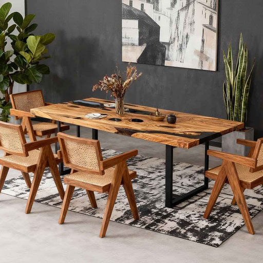 Dining room with wooden table and chairs, plants, and a painting on the wall.