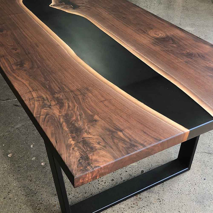 Wooden table with black resin finish on a concrete floor