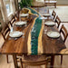 Dining table with a unique design featuring a river of green glass running through it, set for a meal.