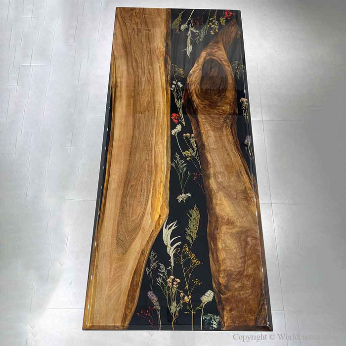 Custom black walnut epoxy river table featuring black resin with preserved flower details and natural wood grain