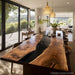 Modern dining room with a long wooden table and large windows overlooking a scenic view.