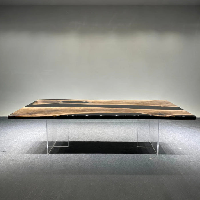 Wooden dining table with black resin inlay on a gray floor and wall.