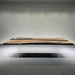Wooden dining table with black resin inlay on a gray floor and wall.