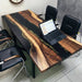 Large custom black epoxy resin river table used as an office conference desk.