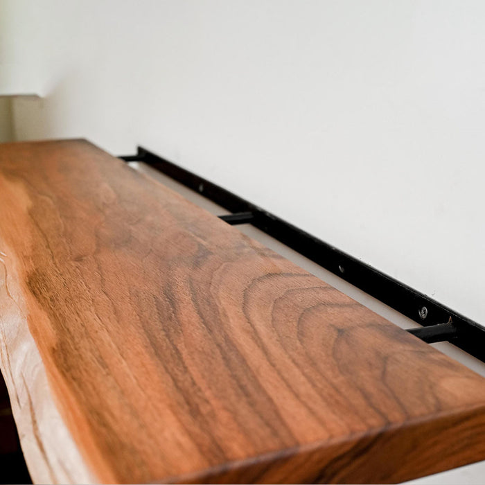 Wooden shelf with black metal bracket against a white wall