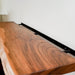 Wooden shelf with black metal bracket against a white wall