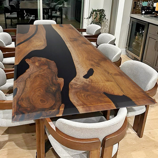 This is an elegant epoxy resin wood table. The table top showcases dark, rich-toned wood with distinct natural grain patterns, complemented by sleek black epoxy resin inlays that add a modern touch. The clear acrylic legs provide a light and airy base, enhancing the overall aesthetic. The combination of the sturdy wood and the glossy epoxy resin creates a durable and visually appealing surface, making it suitable for use as a dining table or in a contemporary office setting. 