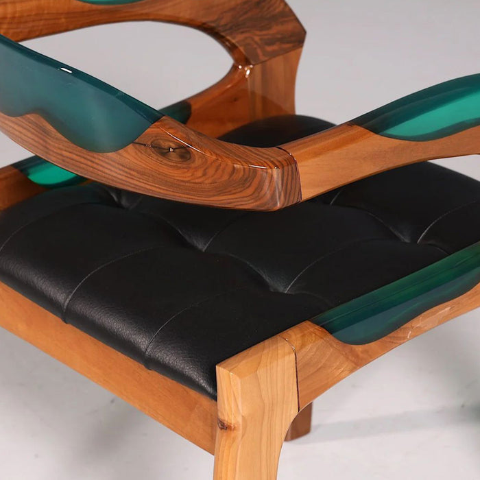 Chair with wooden frame, black cushion, and green armrests on a white background