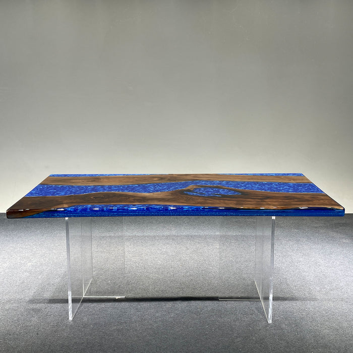 Dining table with blue resin top and wooden accents on a gray floor.