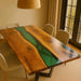Dining table with green epoxy resin inlay in a room with chairs and a lamp.