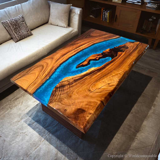 A live edge walnut coffee table featuring a luminous glowing blue epoxy river.