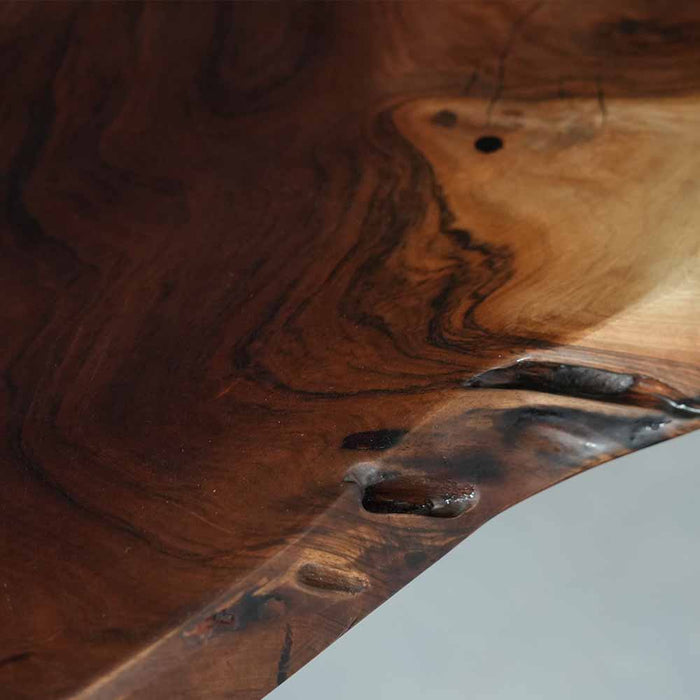 Wooden surface with a river of dark liquid running through it, on a light gray background.