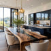 Modern kitchen with a long wooden dining table and chairs, featuring large windows and stylish pendant lights.