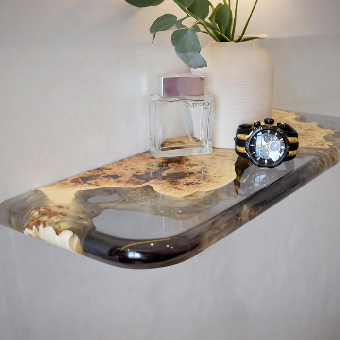 Decorative shelf with a watch, perfume bottle, and plant on a neutral background