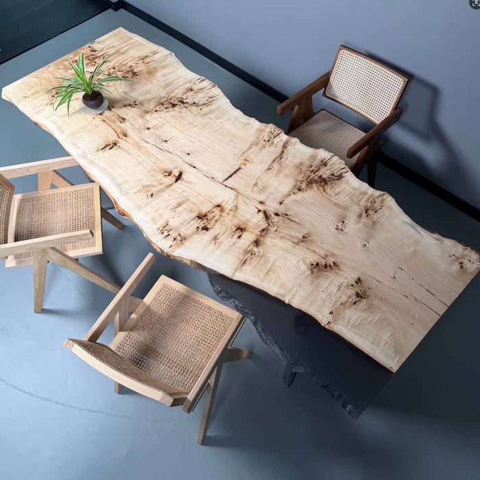 Wooden dining table with natural finish and wicker chairs on a blue floor.