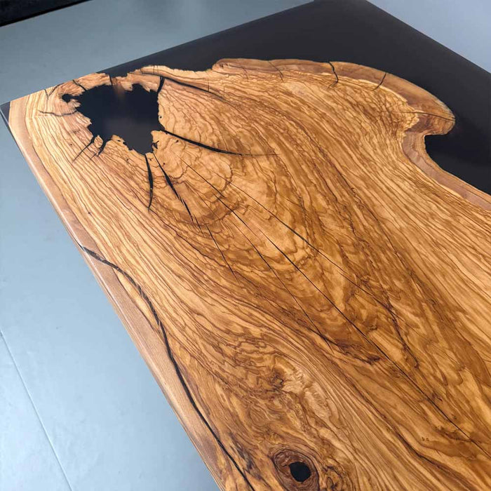 Wooden table with a black resin finish on a light blue surface