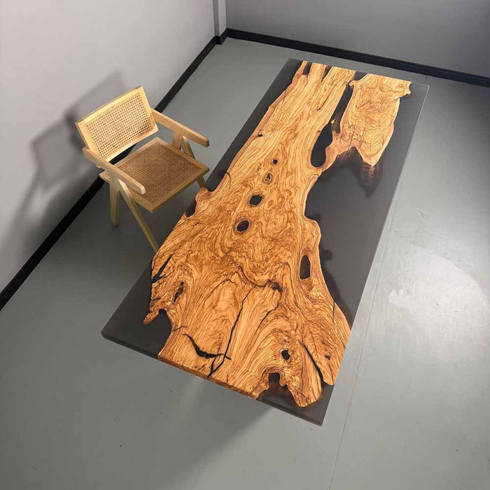 Wooden table with a natural grain pattern and a chair on a gray floor.